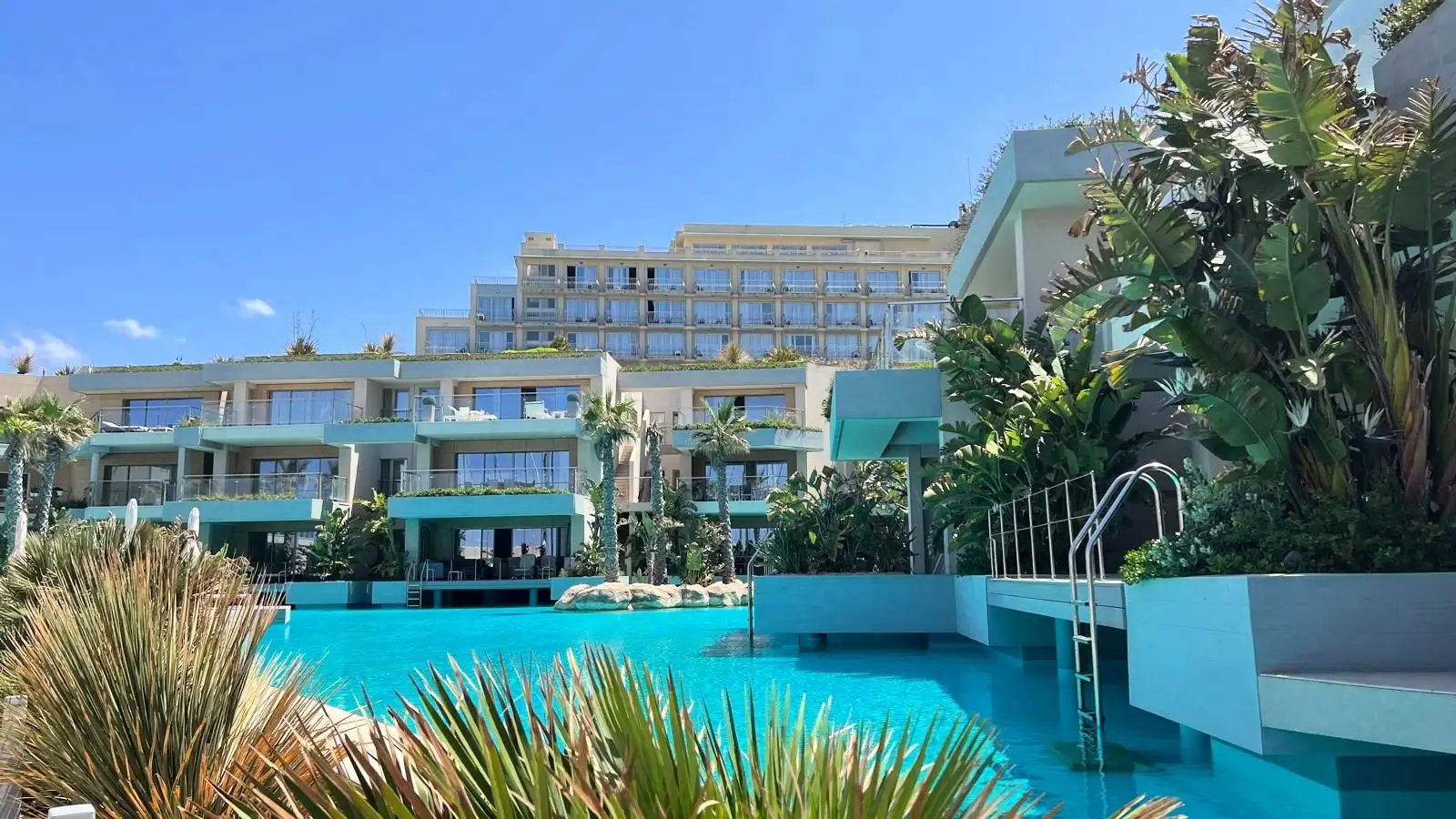 Luksusowy apartamentowiec z basenem i tropikalną roślinnością, idealny na inwestycję lub wakacyjny wynajem w słonecznym klimacie.